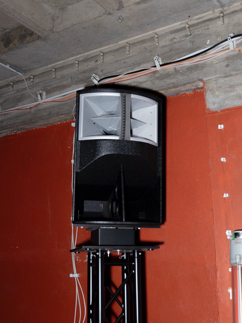 A doorway into a dark basement room lit in deep pink.
